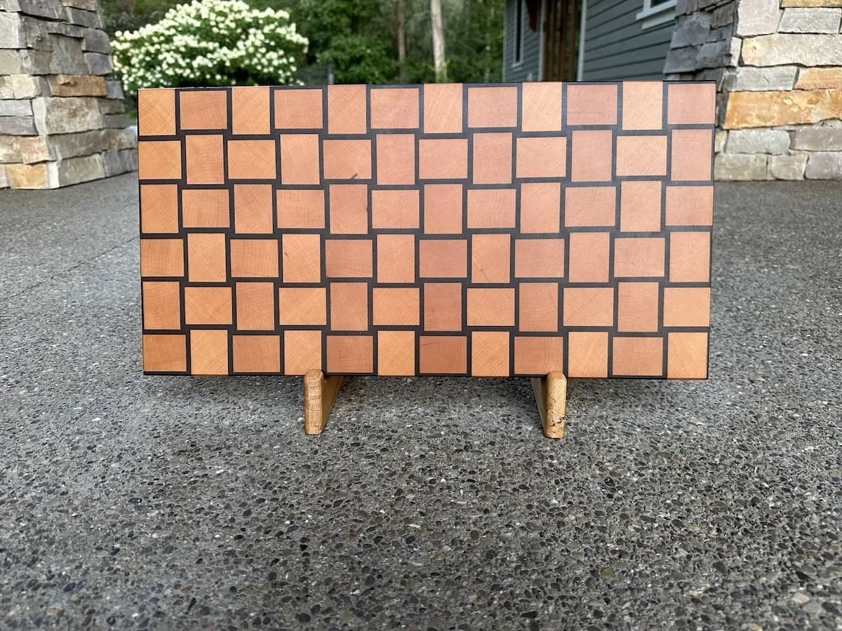 Wooden cabinet with a geometric pattern of square tiles on the front, placed outdoors on a textured surface.