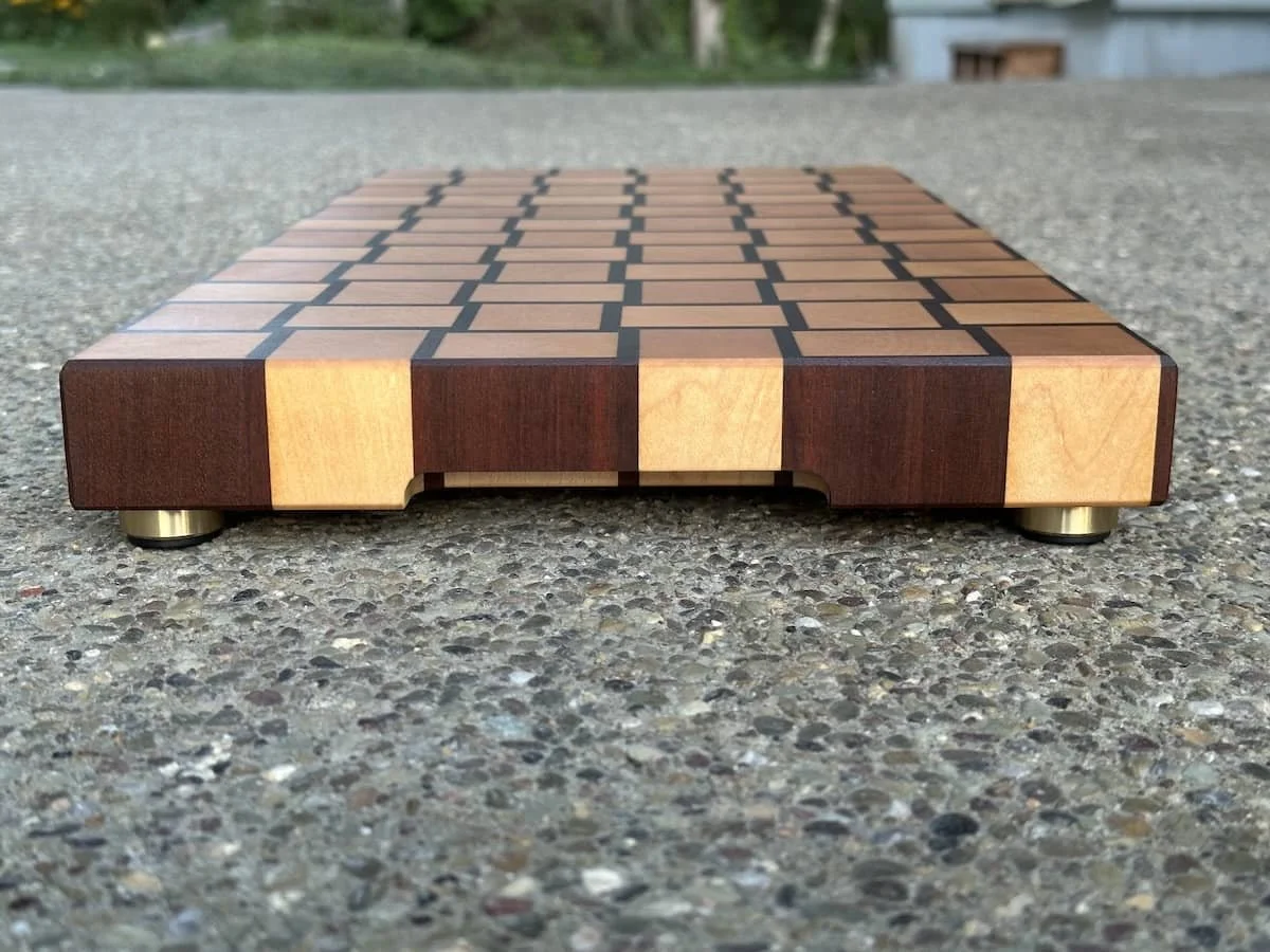 Wooden chessboard with alternating dark and light squares placed on a textured surface, outdoors