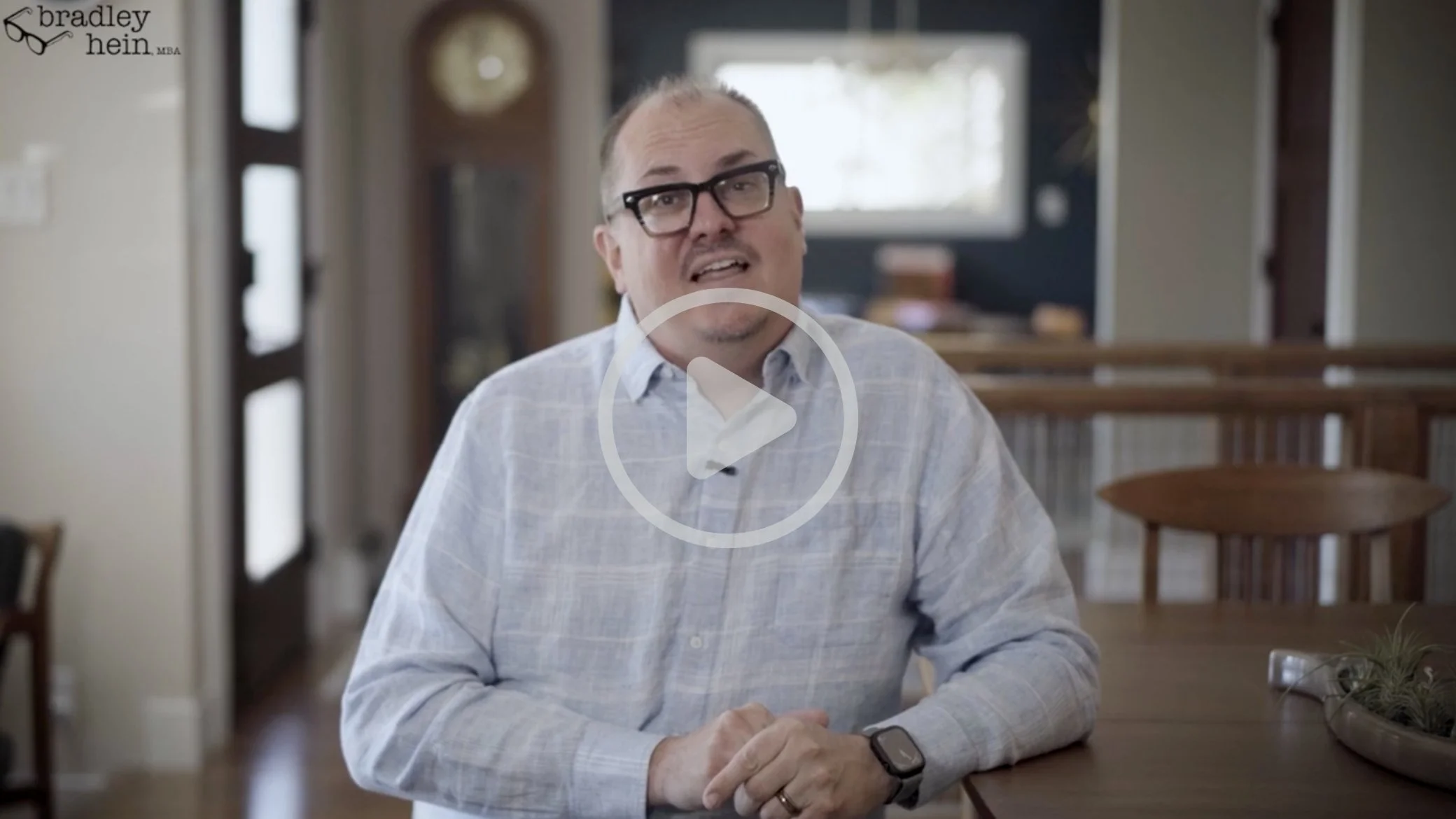 Bradley Hein wearing glasses and a blue plaid shirt and a smartwatch, shares a marketing case study. The integrated digital and print campaign drove real results, bringing more tourists to the town of Taos, New Mexico.