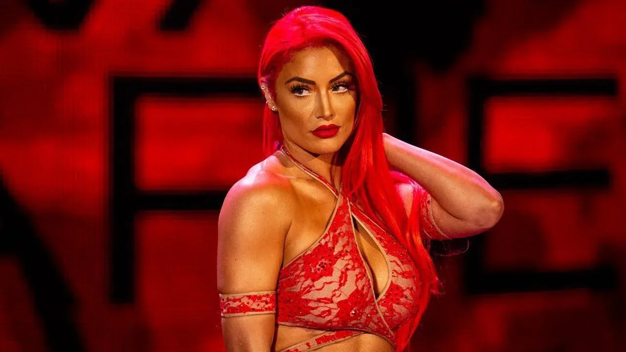 Natalie Eva Marie posing in a red lace outfit with her signature bright red hair.