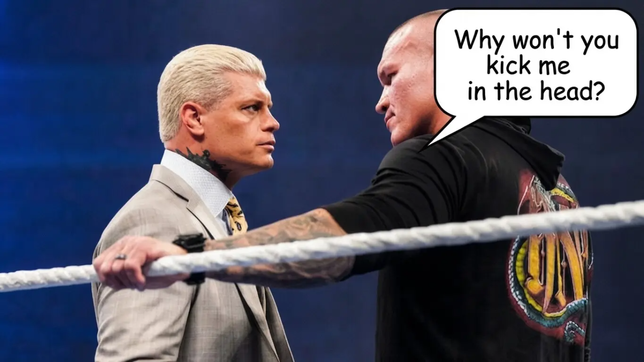 Cody Rhodes in a suit standing across the ring from Randy Orton in a black hoodie, with a comic speech bubble coming from Randy that reads, "Why won't you kick me in the head?"