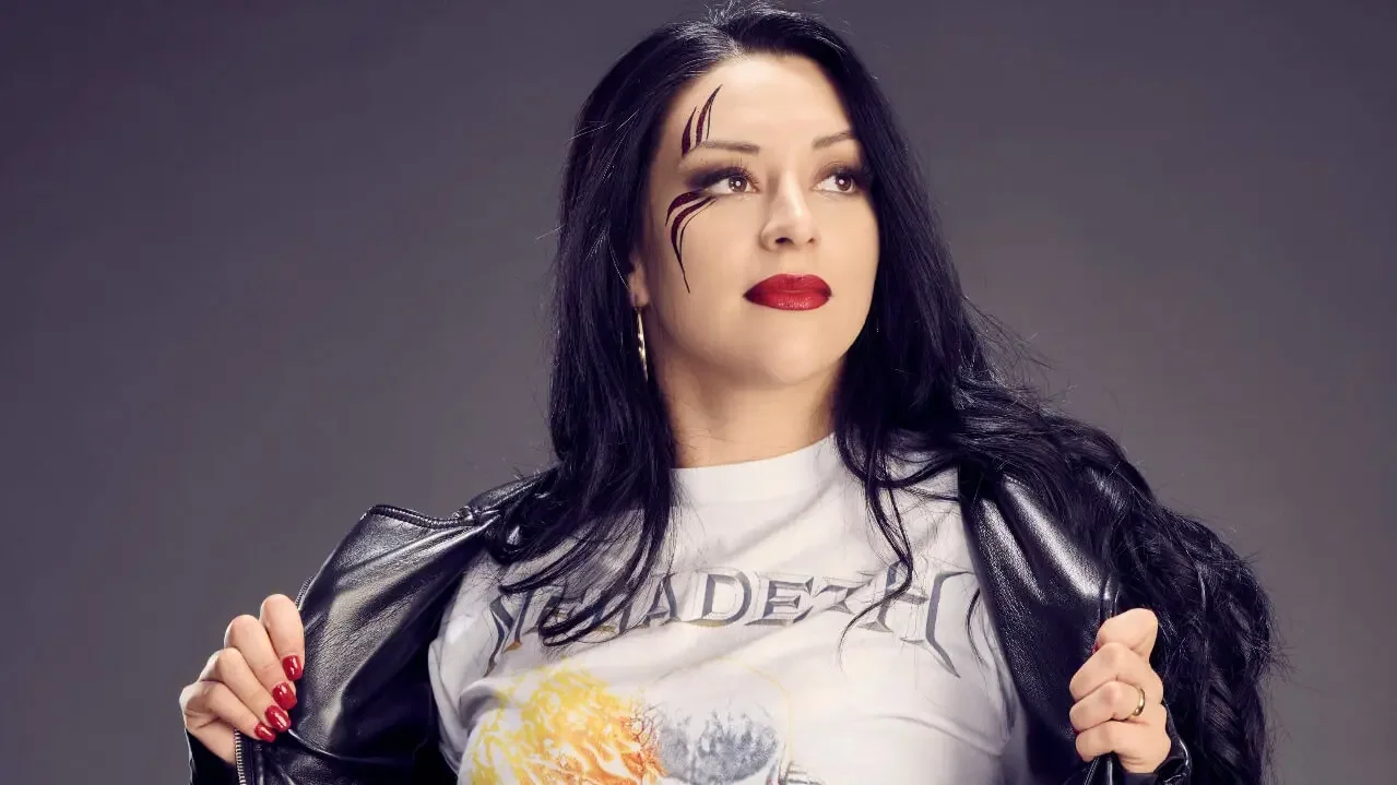 Stephanie Vaquer wearing a Megadeth graphic t-shirt and a black leather jacket with face paint and dark hair