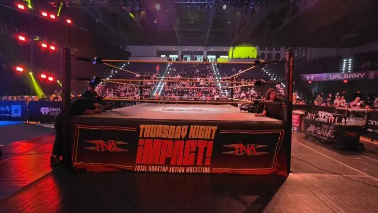 "Wide view of the TNA Impact wrestling ring at the Broadview Center in Albany, New York, showing the Thursday Night Impact branded apron and noticeably light crowd attendance during the 2026 TV taping."