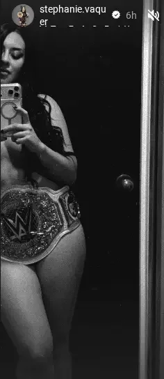 Stephanie Vaquer taking a black-and-white mirror selfie wearing a championship belt.