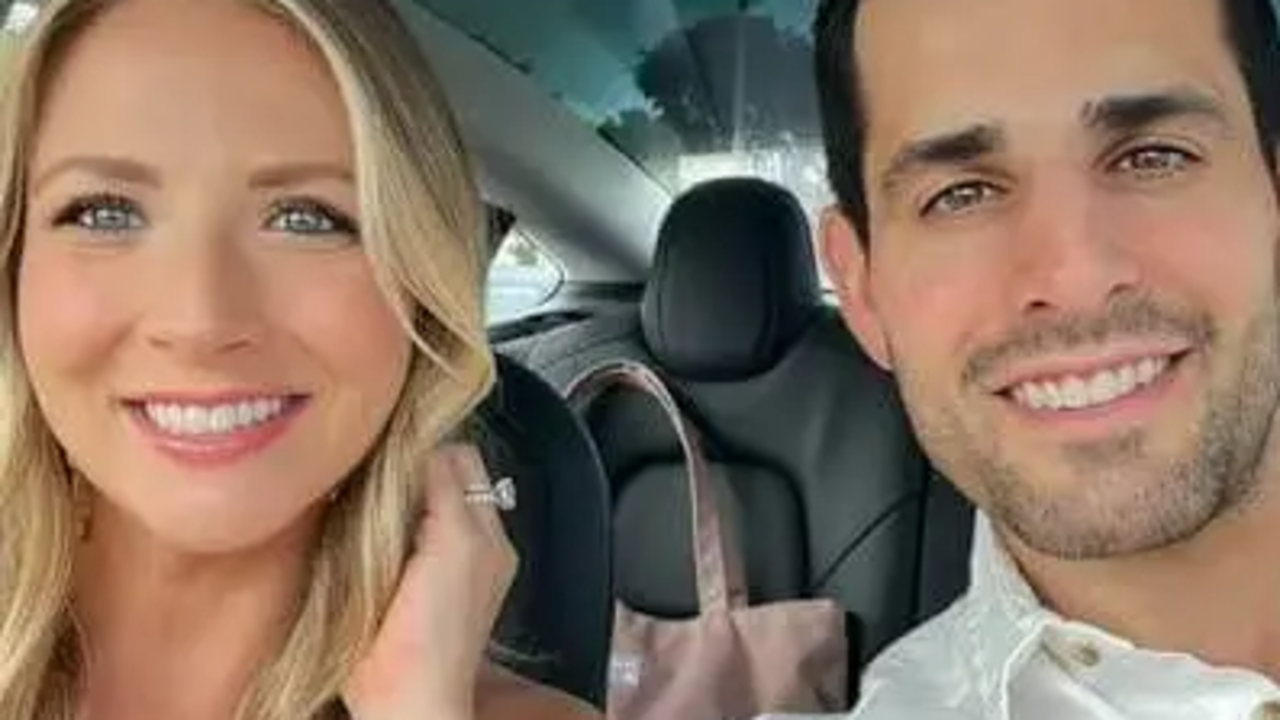 Chris Van Vliet and his partner smiling together inside a vehicle.