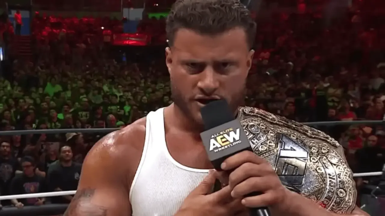 MJF cutting a fiery promo into an AEW microphone with a championship belt draped over his shoulder in front of a massive crowd at Arena Mexico during AEW Grand Slam Mexico.