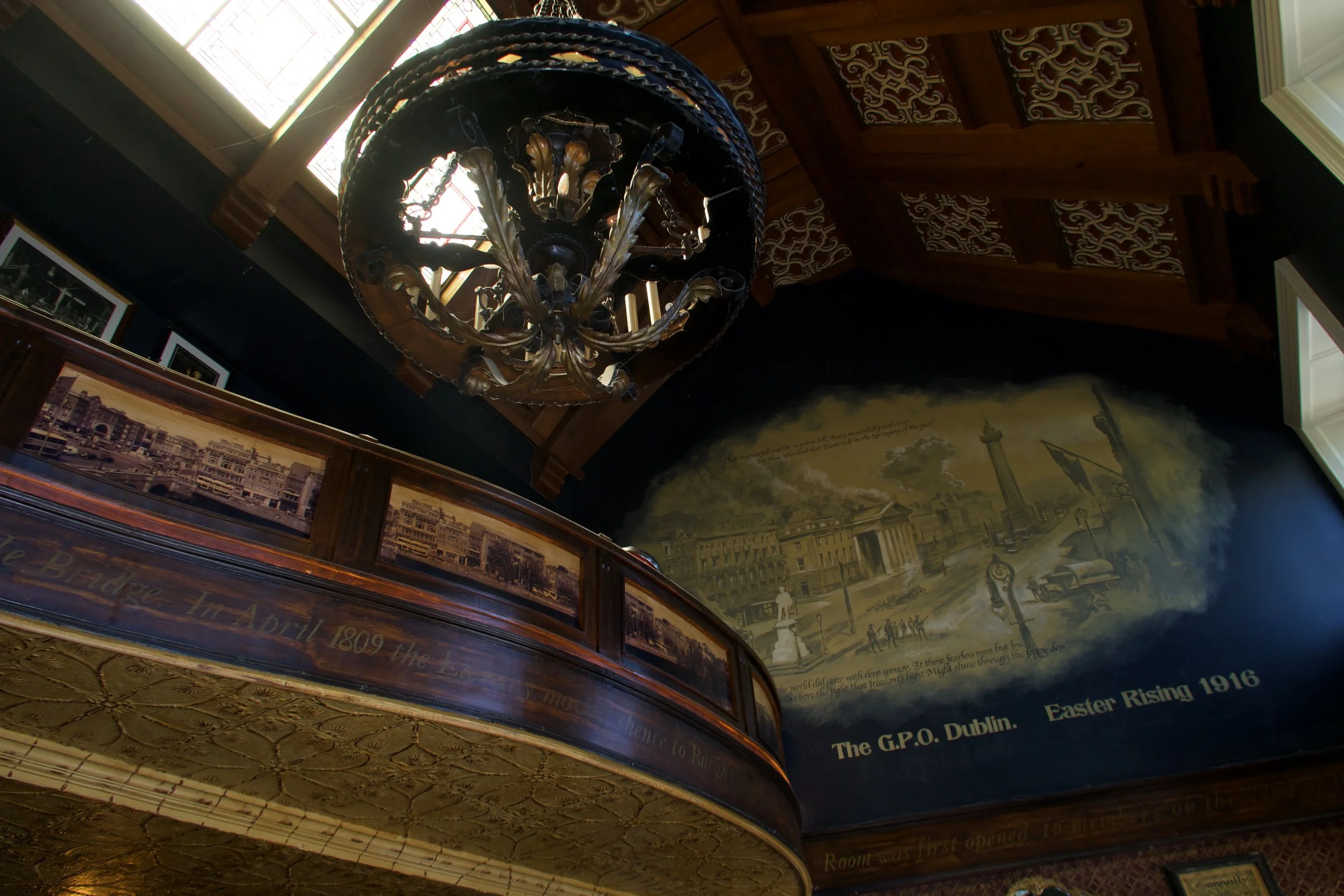 Dimly lit restaurant interior with candles on tables and large windows showing greenery outside.