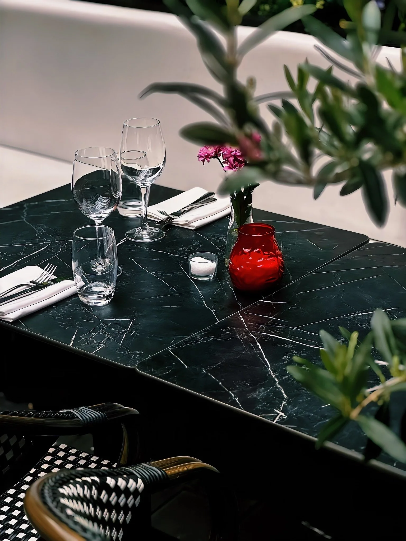 Elegant restaurant dining area with white tablecloths, glassware, and cutlery, dim ambient lighting, and a dark interior design.