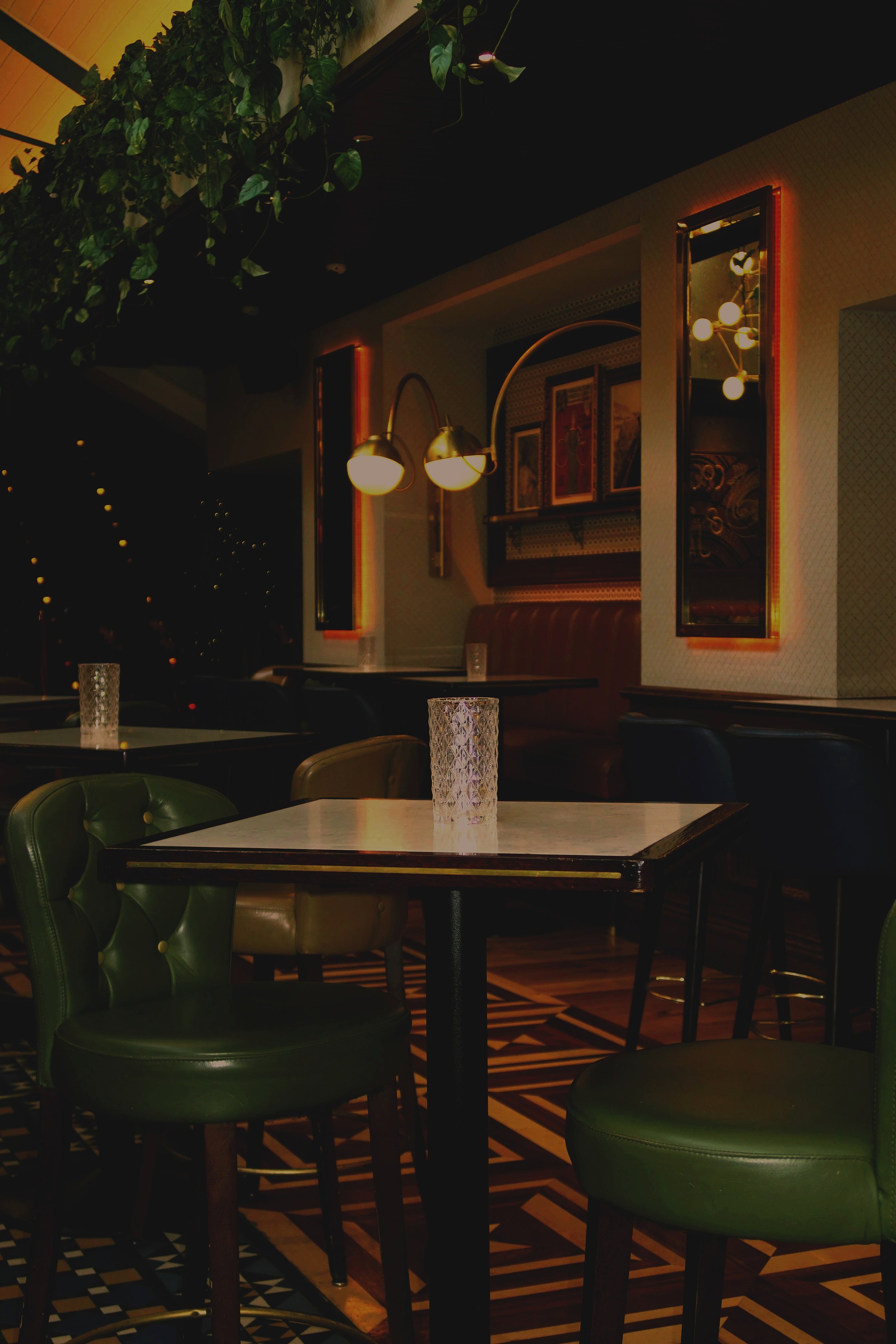 A wall covered in lush green tropical plants with a neon sign that says 'Smile' in the center.