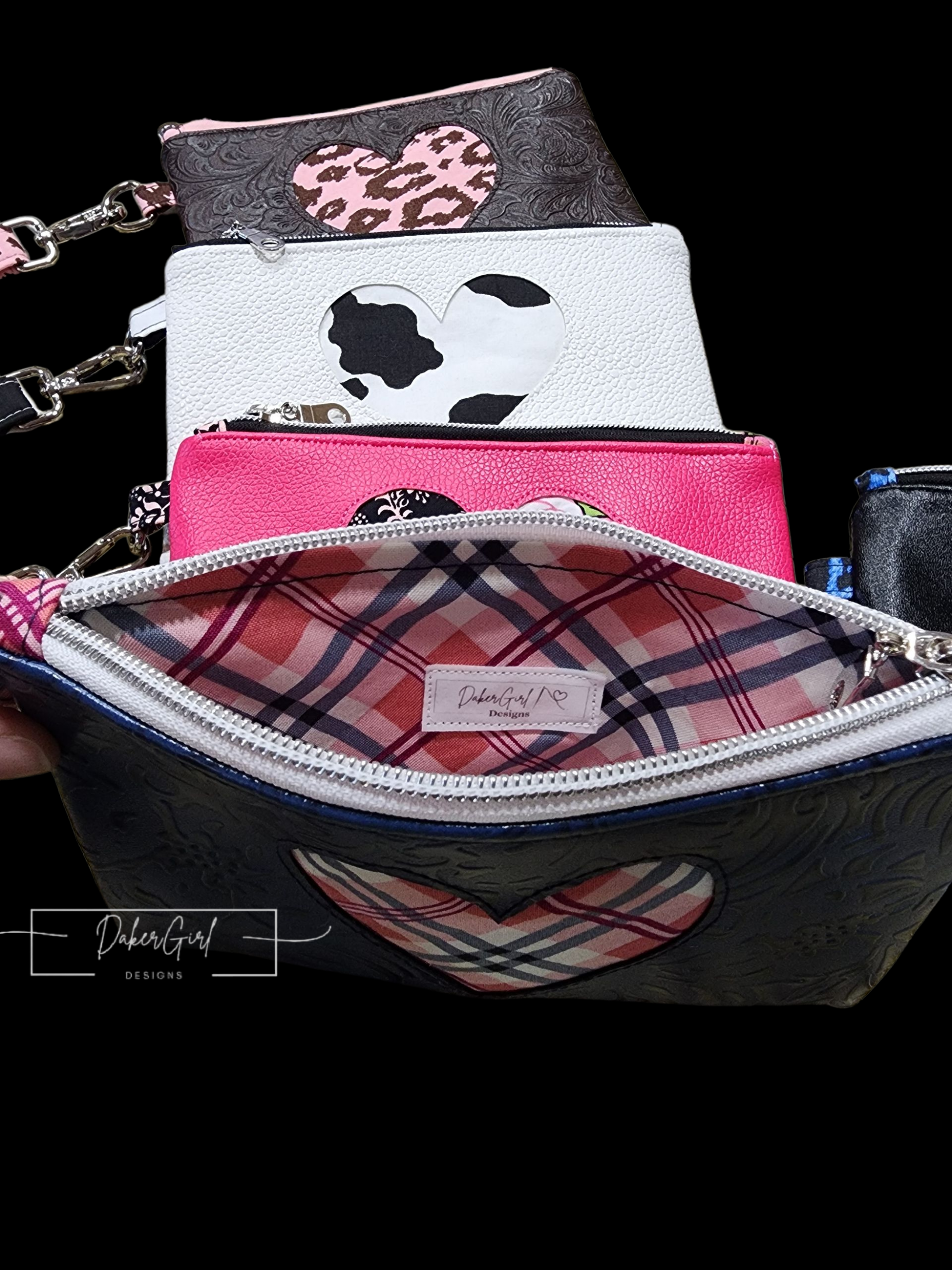 Several small handbags with heart cutouts, patterned with animal prints, stacked on black background, with a larger purse with a heart logo and plaid interior in front.