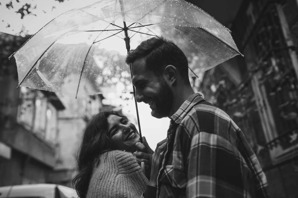 A couple sharing a moment under an umbrella in the rain on a city street.