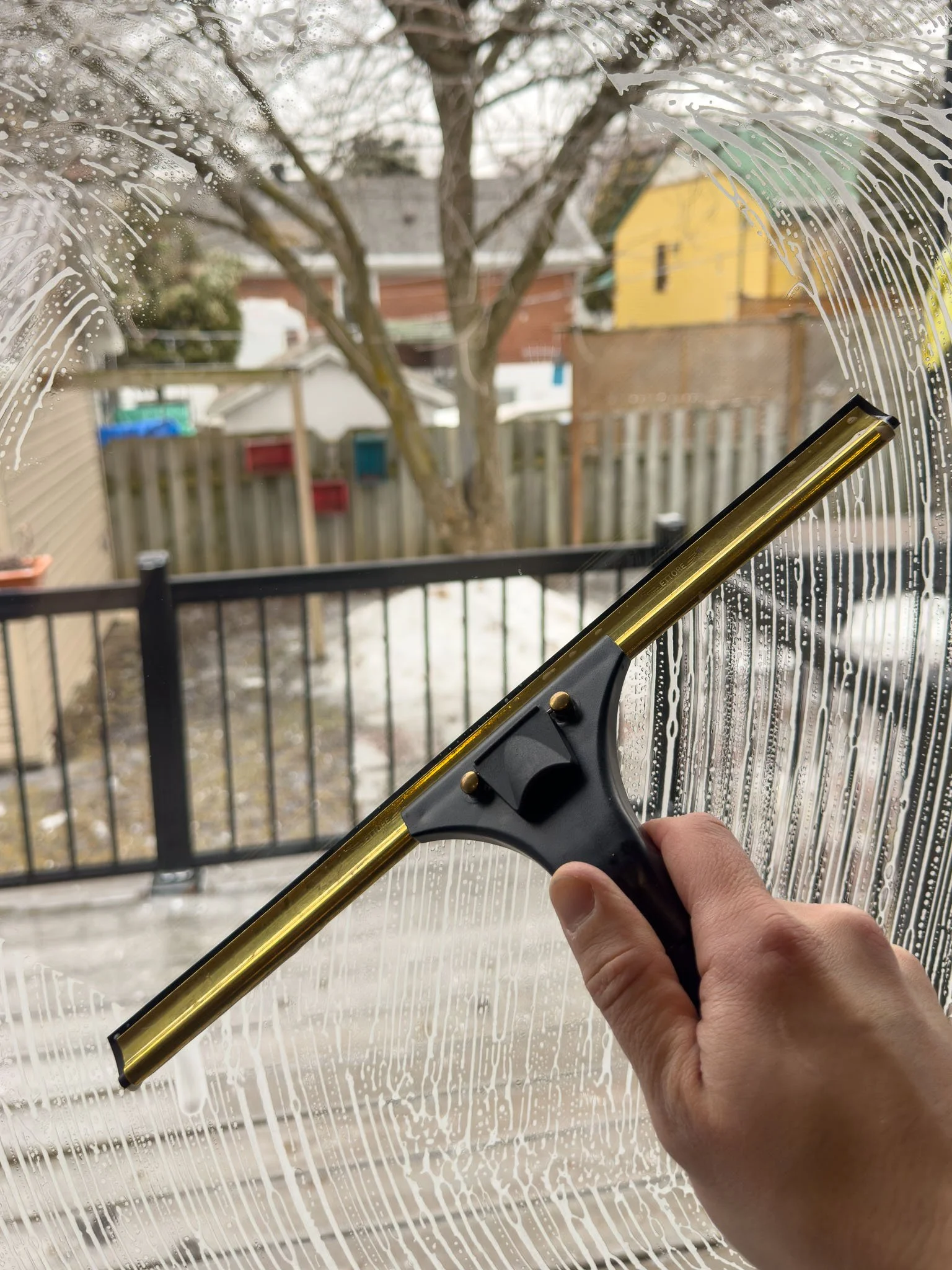 Nettoyage de vitres résidentiel avec raclette professionnelle pour une vue impeccable sur la cour à Montréal.