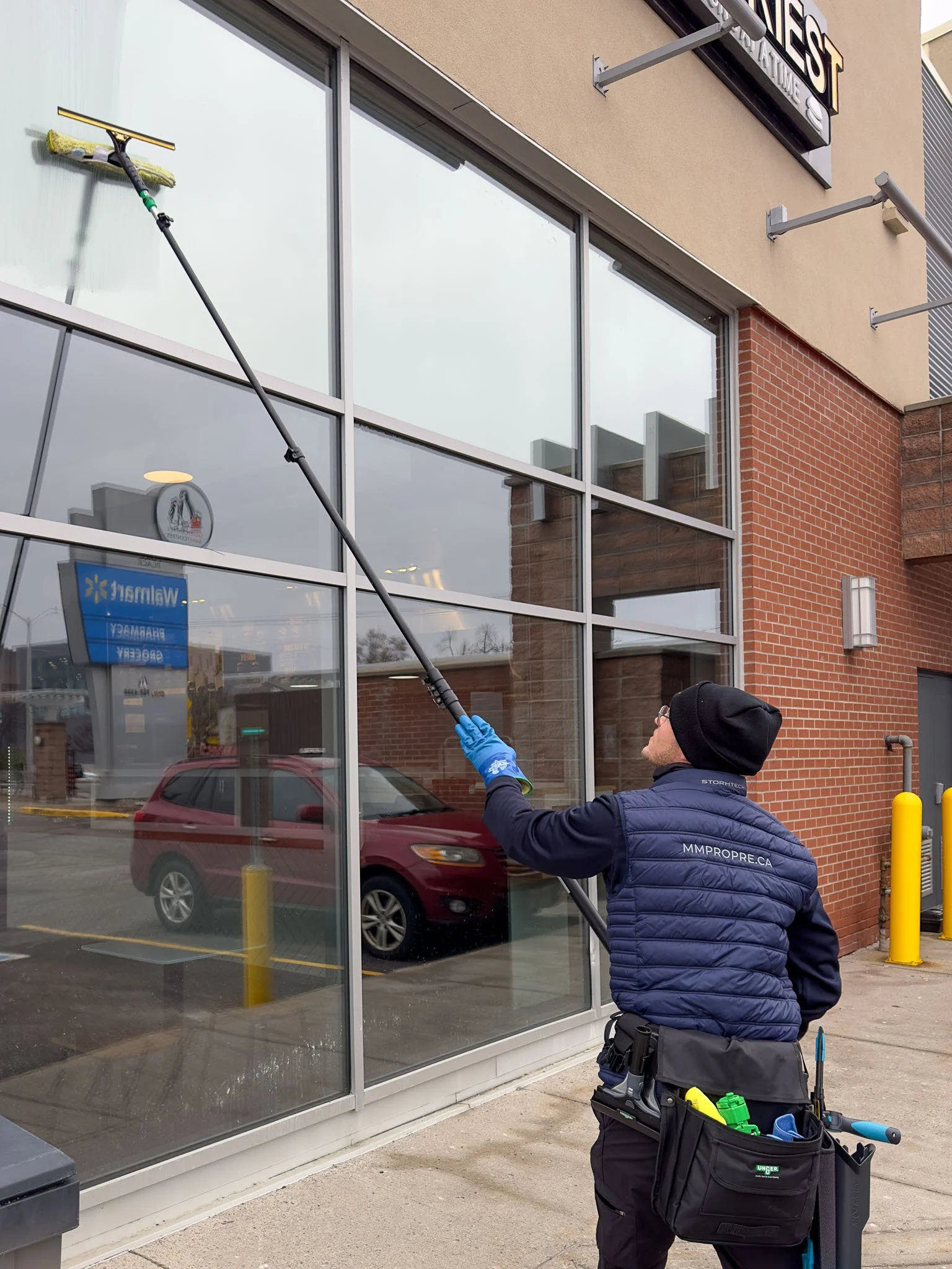 Lavage de vitres commercial à Montréal. Entretien MM Pro utilisant une longue perche pour nettoyer les vitrines extérieures en toute sécurité.
