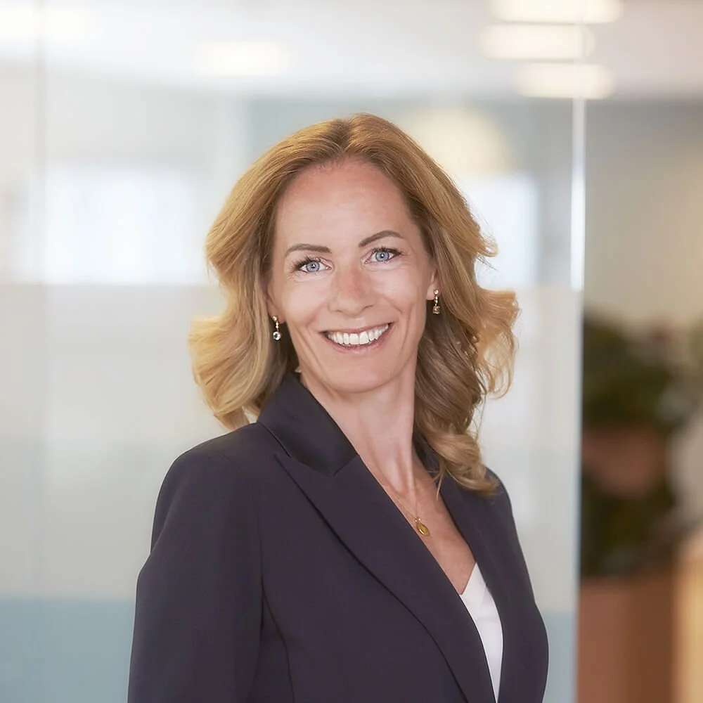 Professional woman with blonde hair smiling in an office setting.