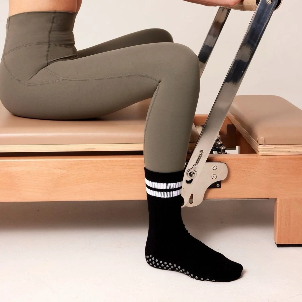 Person performing physical therapy on a wooden treatment table, with their legs bent at the knees and wearing black socks with white dots.