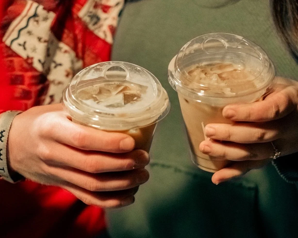 A house situated on a green hillside with snow-capped mountains in the background under a cloudy sky.
