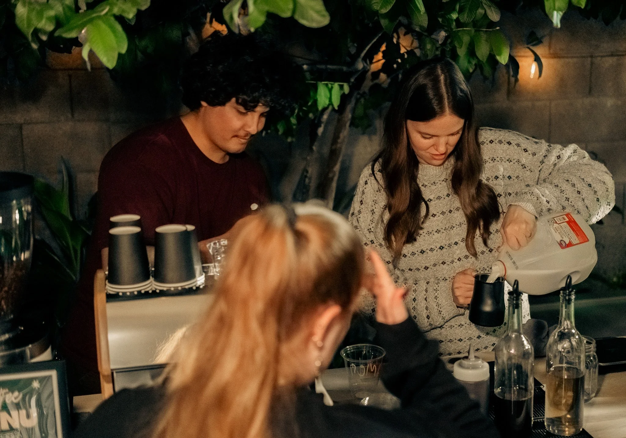 Scenic landscape of a large lake with green hills in the foreground and rugged mountains in the background under cloudy sky.
