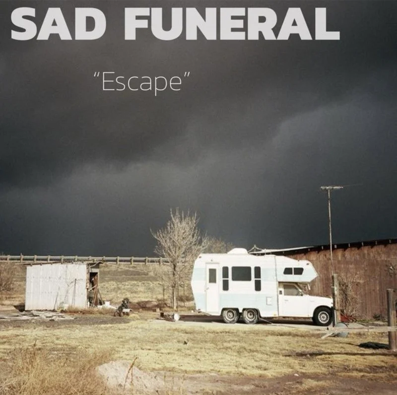 A dark, stormy sky over a rural scene with an RV, a tree, a small shed, and a wooden fence. The image has text that reads 'SAD FUNERAL' and 'Escape'.