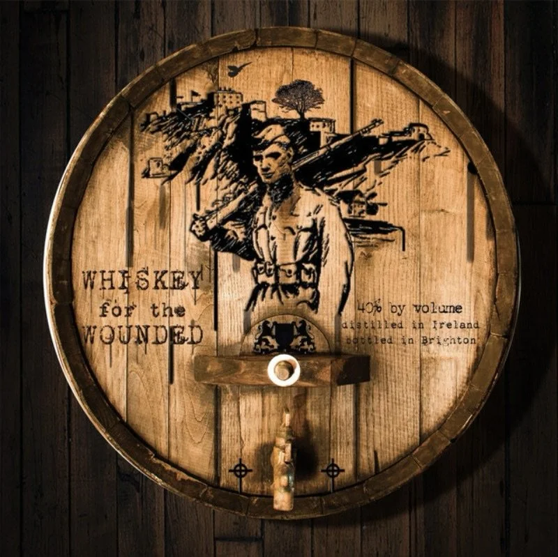 Rustic wooden barrel with a printed design featuring a soldier holding a rifle, along with text about whiskey, Ireland, and Brighton.