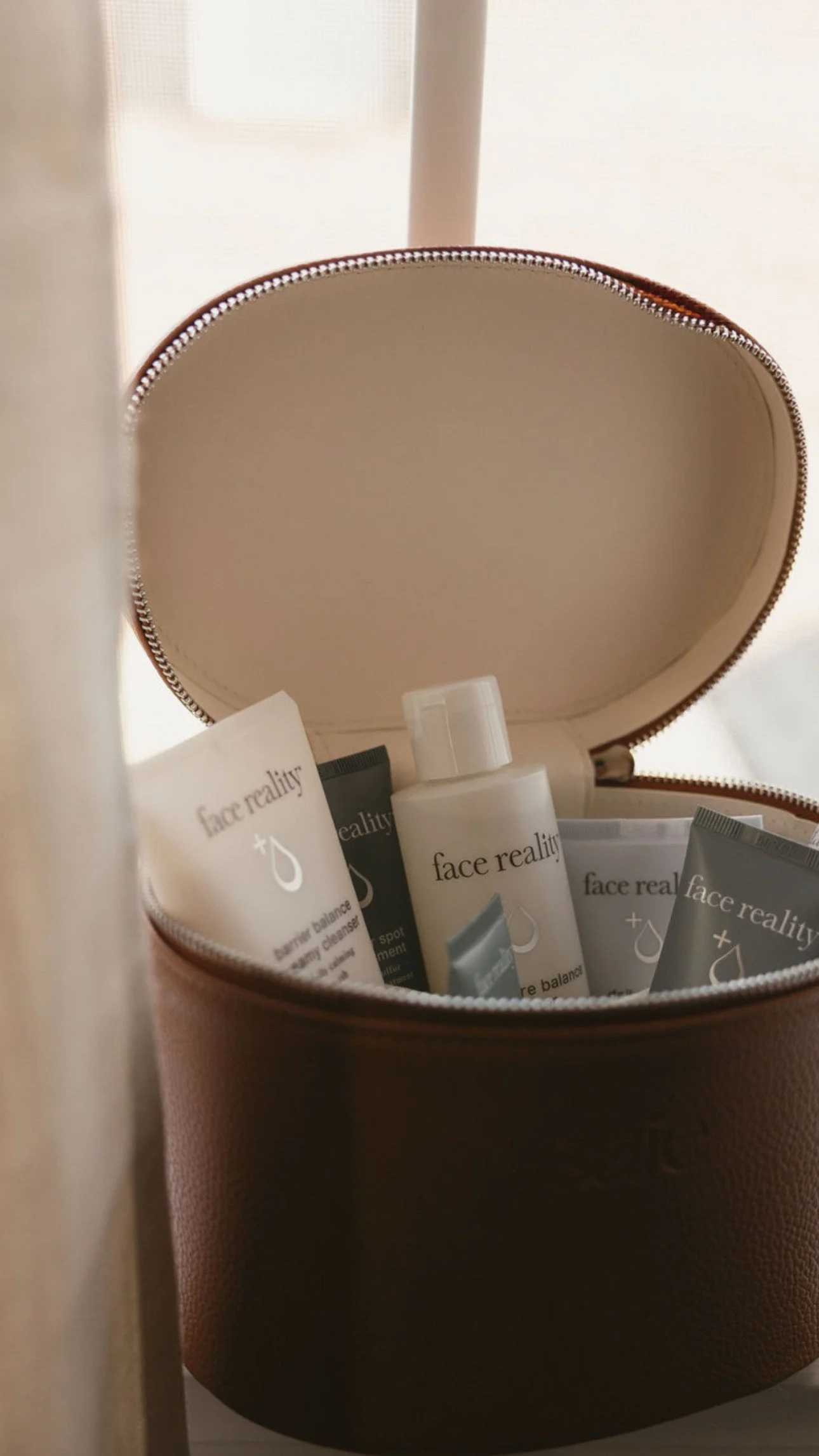 An open round makeup bag containing skincare products, including face reality bottles and tubes.