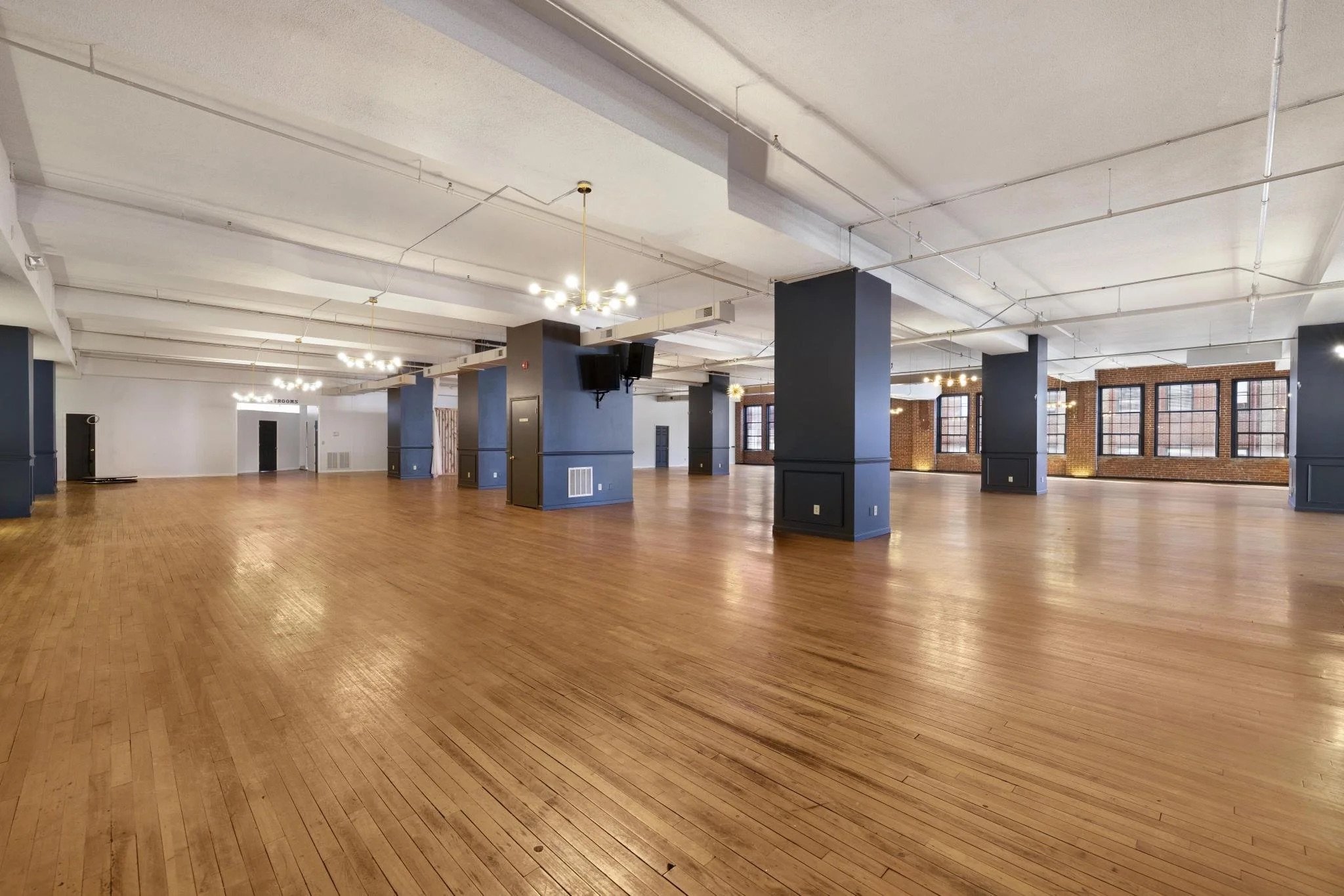 Interior view of Monarch on Main showing hardwood floors, brick walls, and modern chandeliers in a restored 1920s downtown Johnson City building.