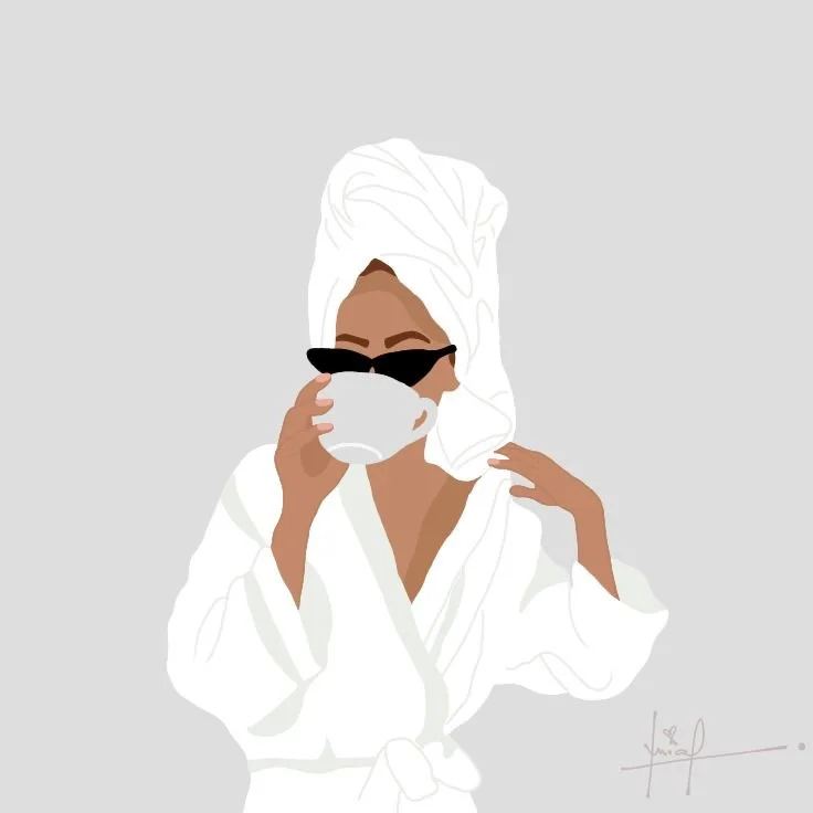 A woman with a towel wrapped around her head, wearing sunglasses, and holding a cup to her lips, dressed in a white robe.