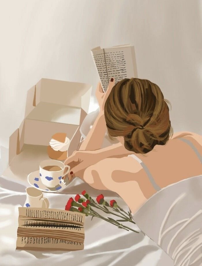 A person with brown hair in a bun, reading a book, surrounded by a cup of coffee, a cupcake, a small pitcher, a bouquet of red flowers, and an open cardboard box, with a white bed or table surface.