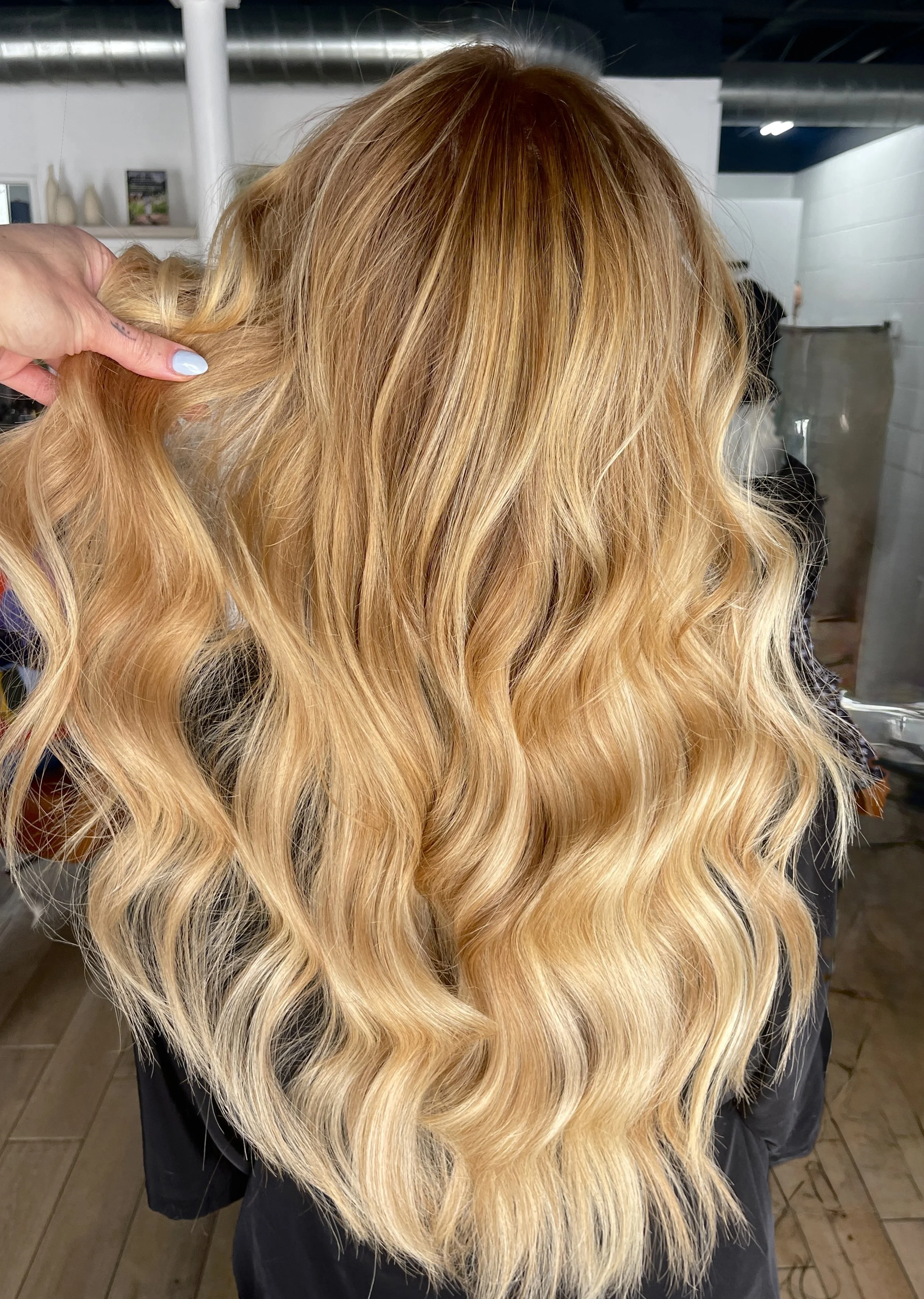 Back view of a woman with long, wavy blonde hair.