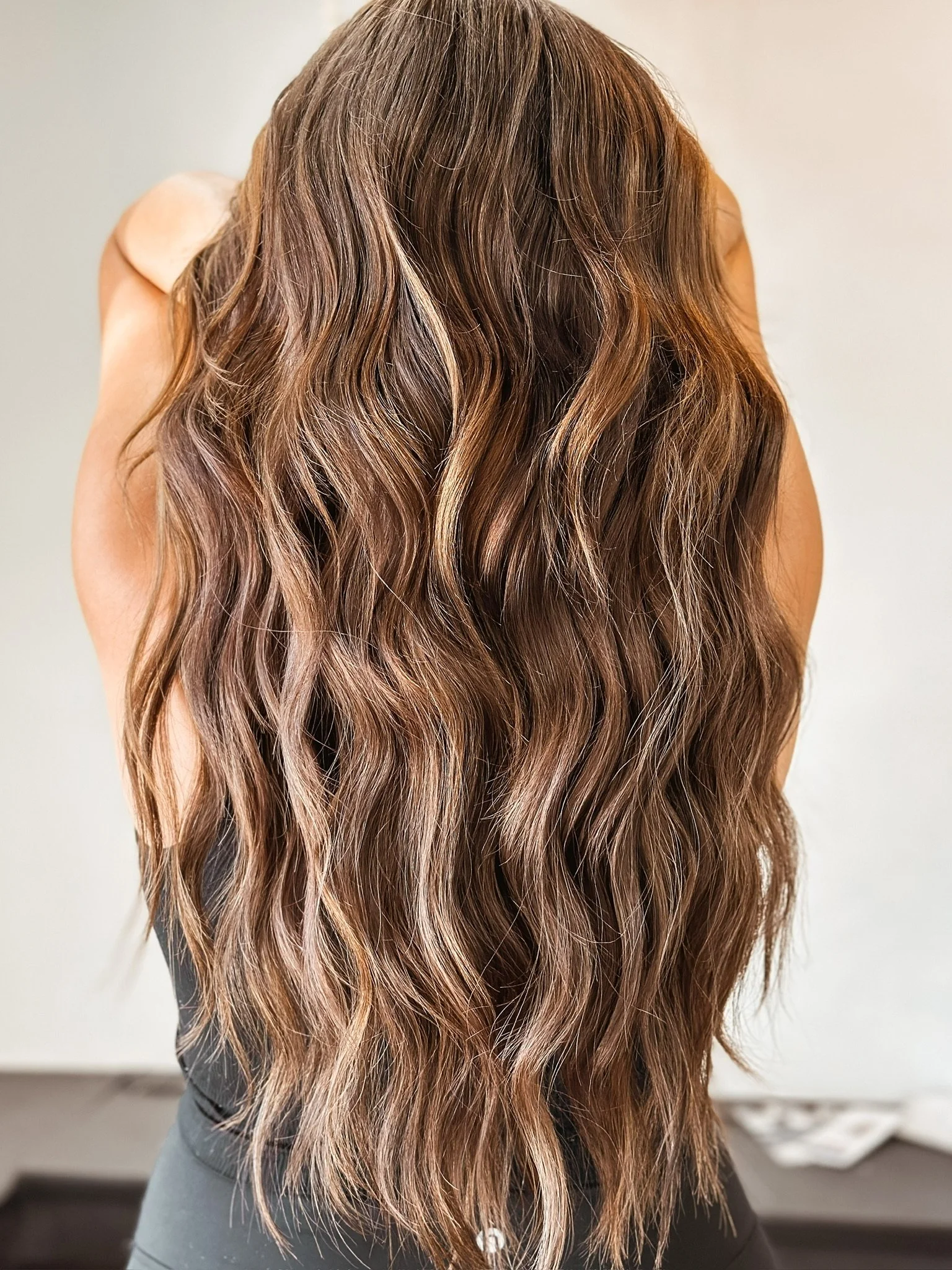 Long wavy hair with highlights on a woman seen from behind.
