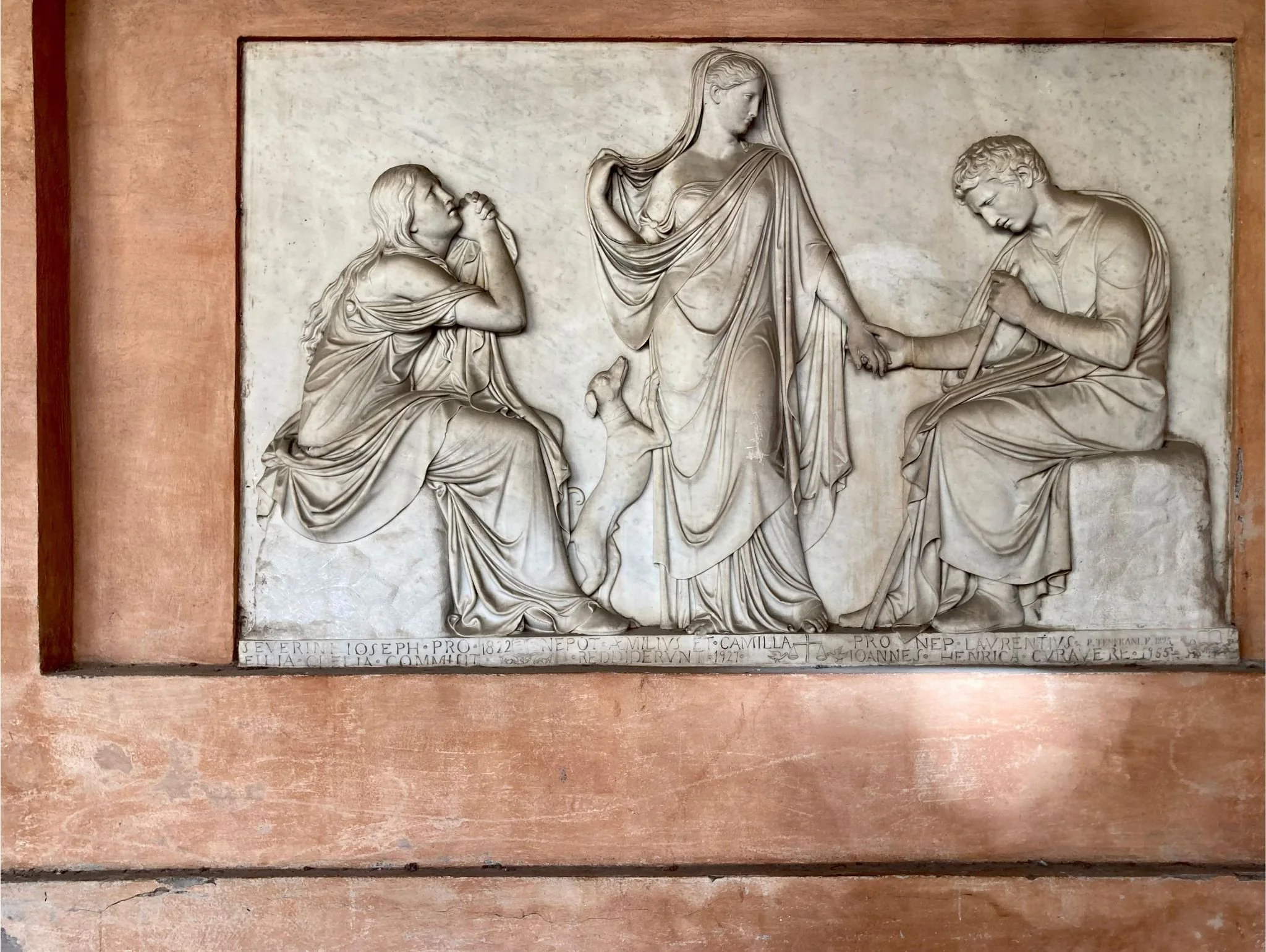 Relief en pierre représentant la Cène, avec plusieurs figures humaines, dont une femme à gauche, une femme centrale et un homme à droite, tenant une croix.