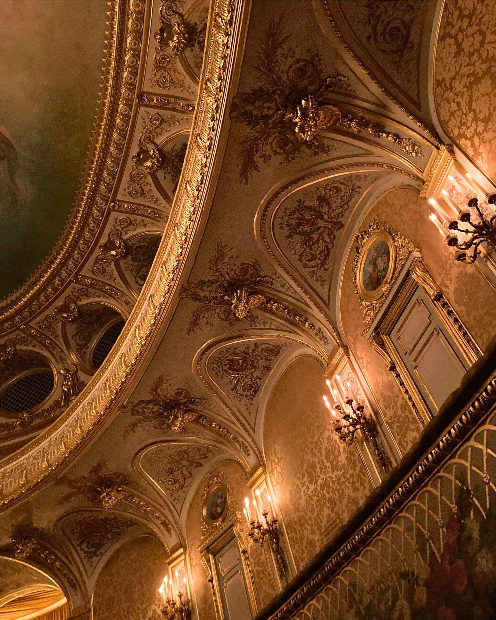 Intérieur d'un théâtre élégant avec des décorations dorées, des moulures élaborées et des lustres en chandeliers.