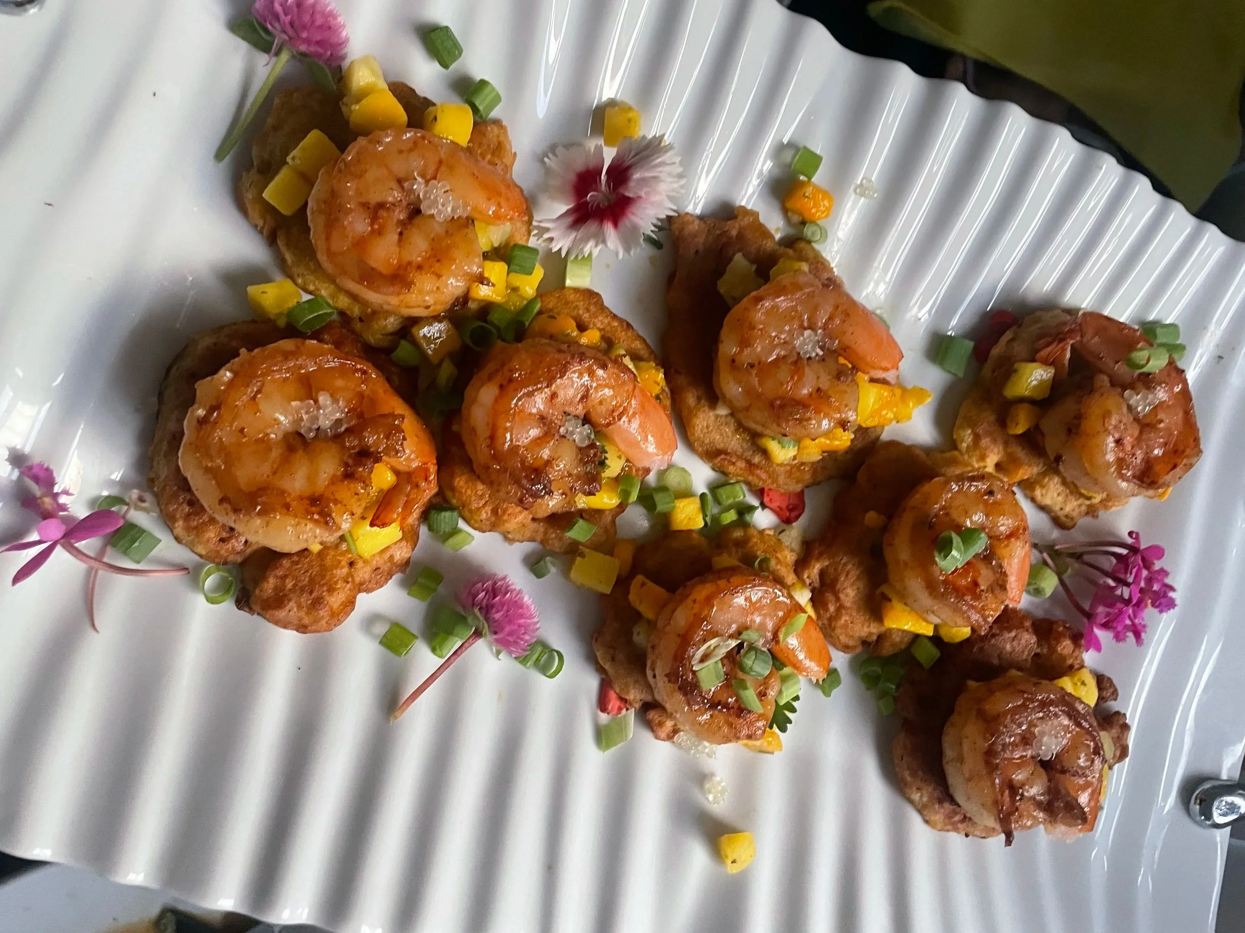 Bite-sized shrimp appetizers with bell peppers, green onions and pink flowers.