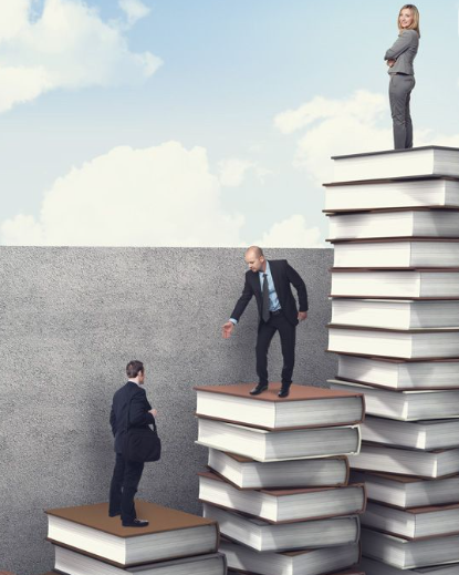 Businesspeople standing on large stacked books against a sky background, with one person standing on top of a tall stack of books.