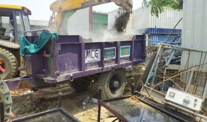 Construction site with a purple dump truck, excavator, and discarded household appliances.
