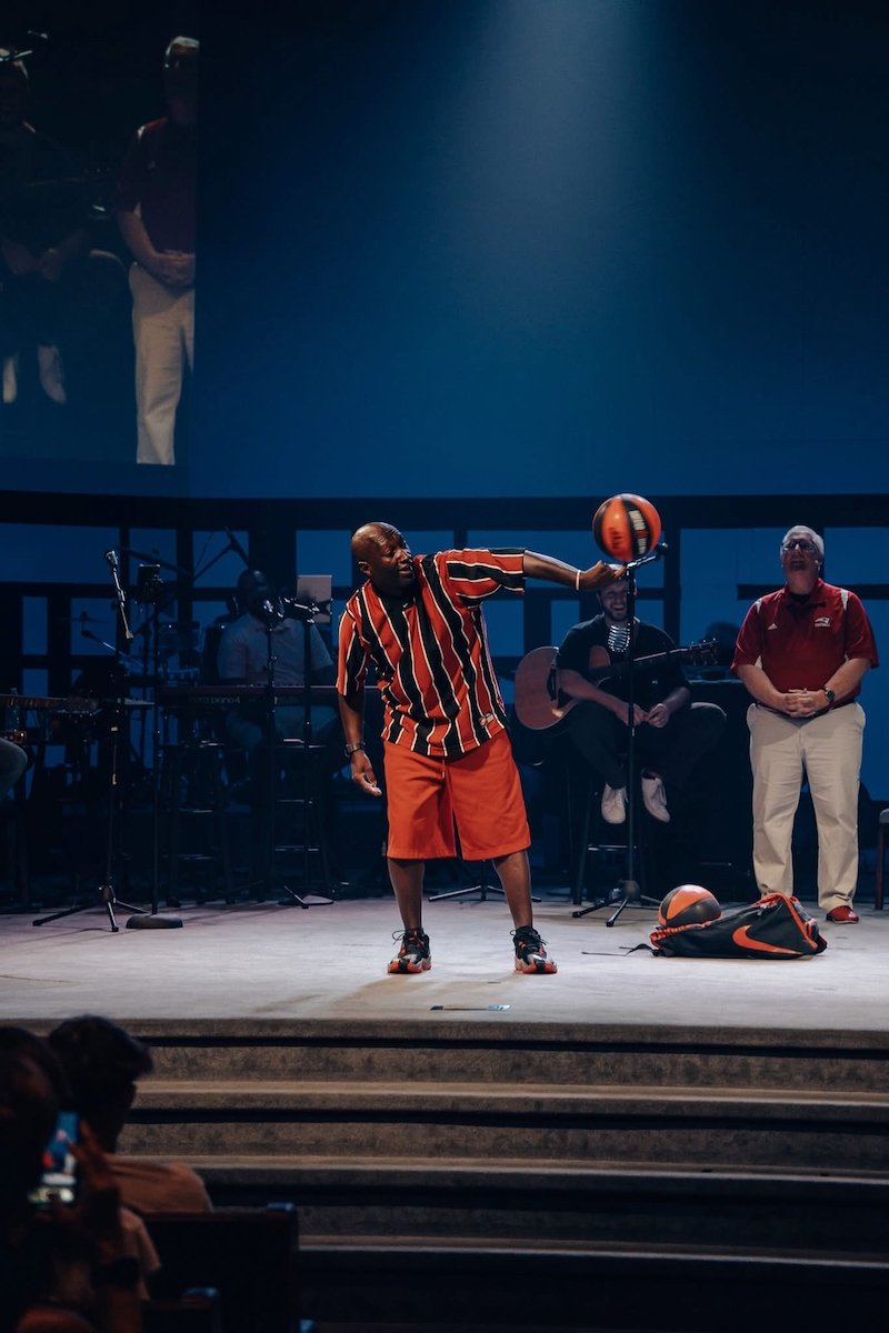 Inspirational presenter Dexter Williams spins two basketballs for a church audience