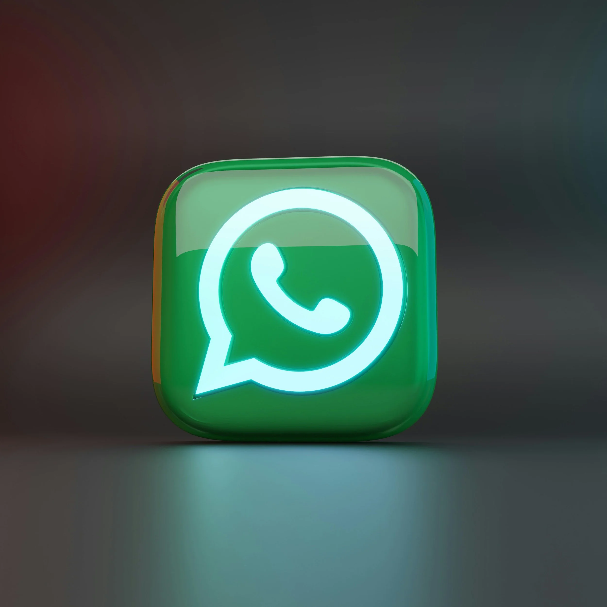 Green illuminated smartphone with a messaging app icon on a dark surface.