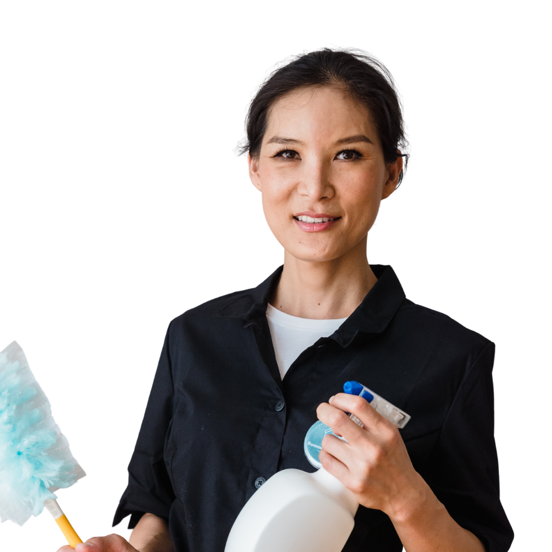 A woman holding cleaning supplies, including a blue feather duster, a spray bottle, and a roll of paper towels, smiling at the camera.