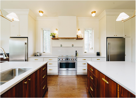 Modern kitchen with white cabinets, stainless steel appliances, and dark wood island counters.