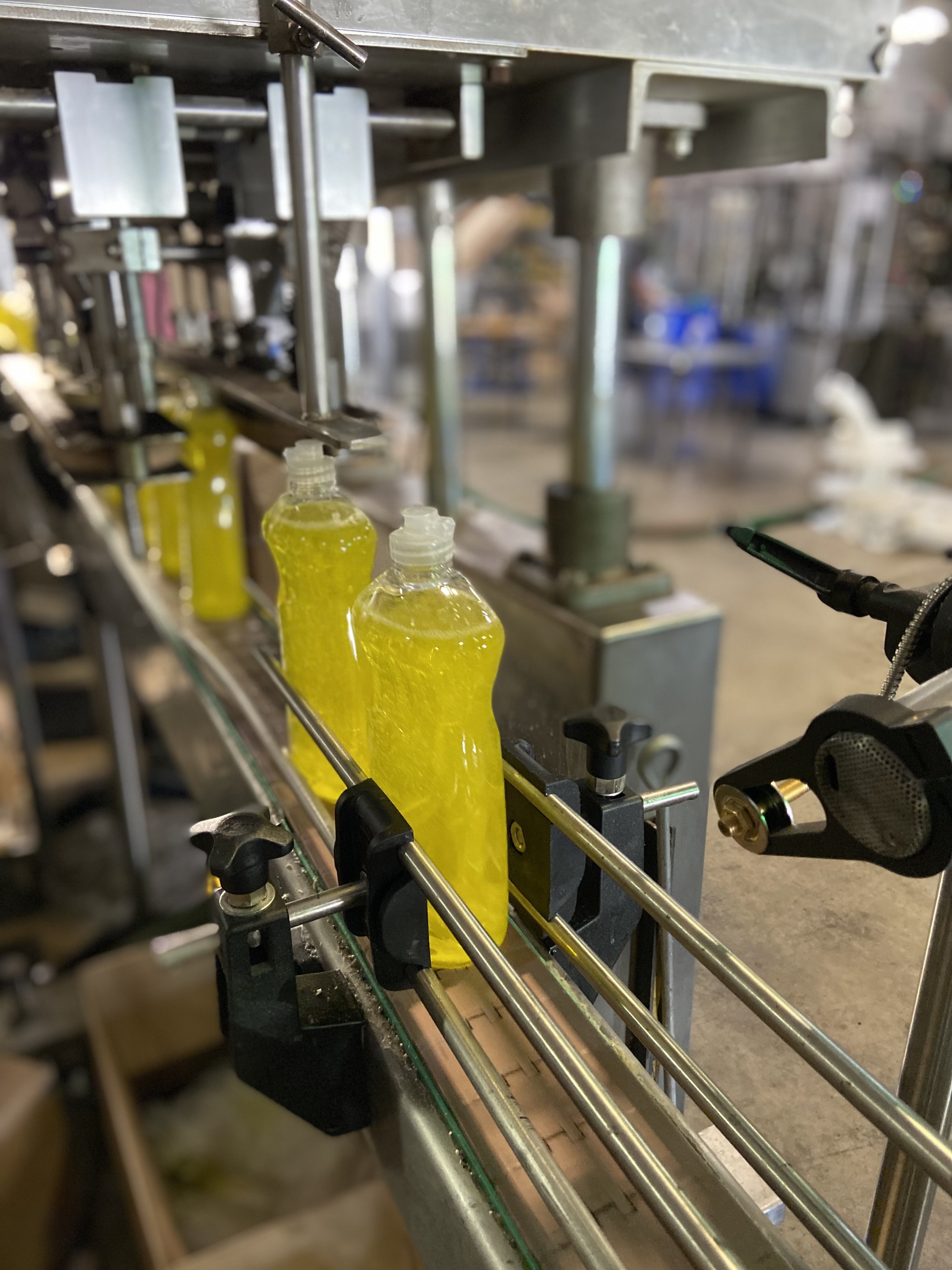 Yellow liquid soap bottles on a conveyor belt in our plant.