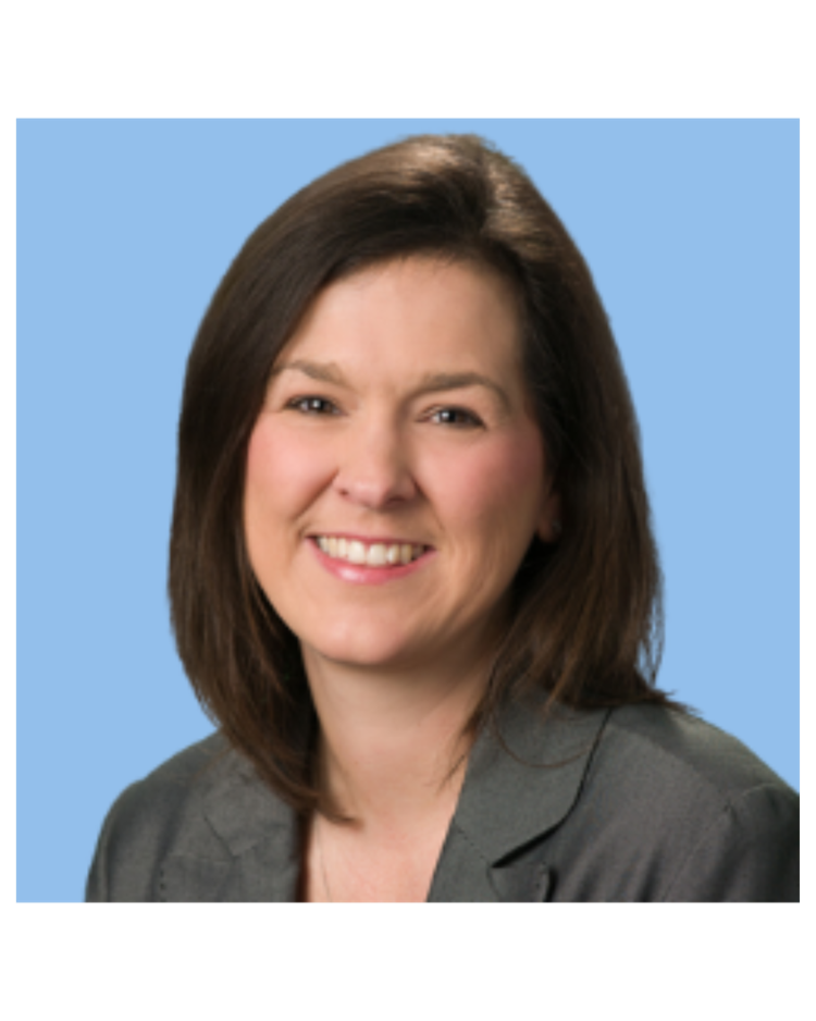 A smiling woman with shoulder-length brown hair, wearing a grey blazer, against a light blue background.