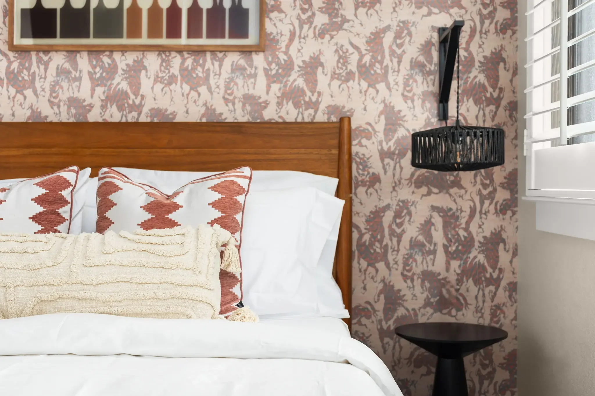 Airbnb bedroom detail with bold western horse wallpaper, wood headboard, and layered textile pillows — Austin TX.