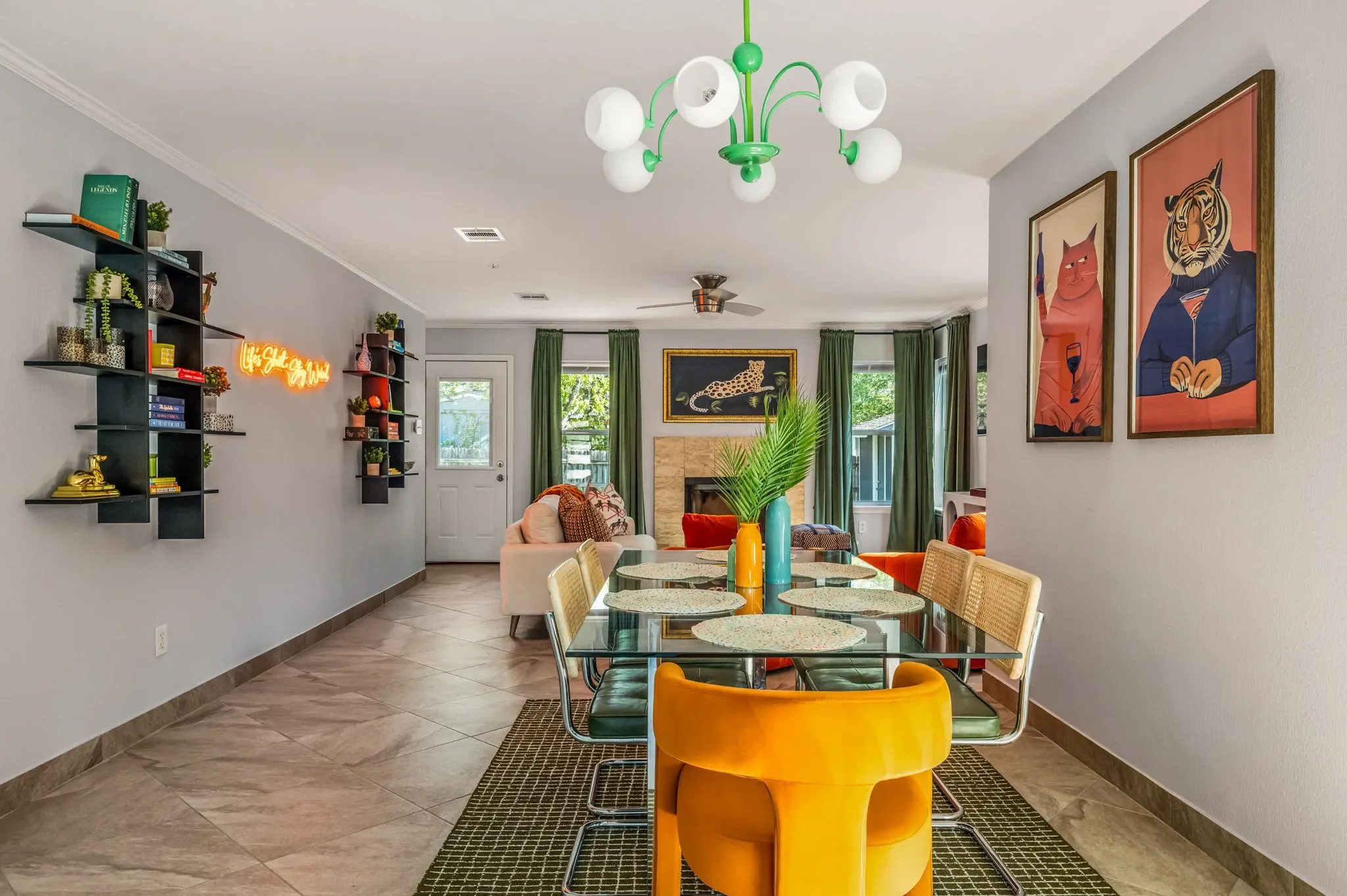Open-concept living and dining room with retro mid-century modern decor, colorful accents, a statement light fixture, animal wall art, and decorative shelves.