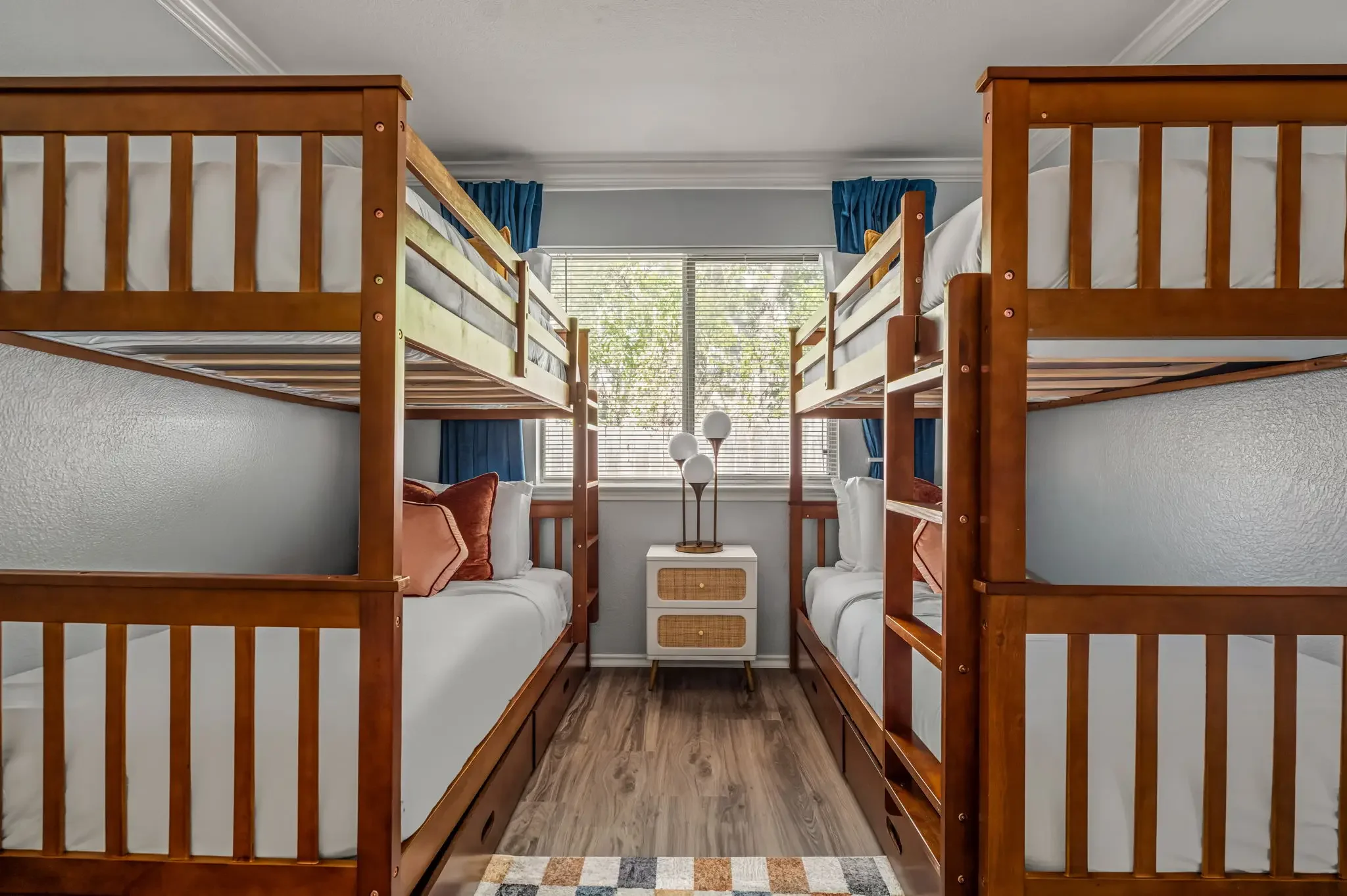Short-term rental bunk room design with two sets of wood bunk beds, bright window, and kids-friendly decor — Austin TX.