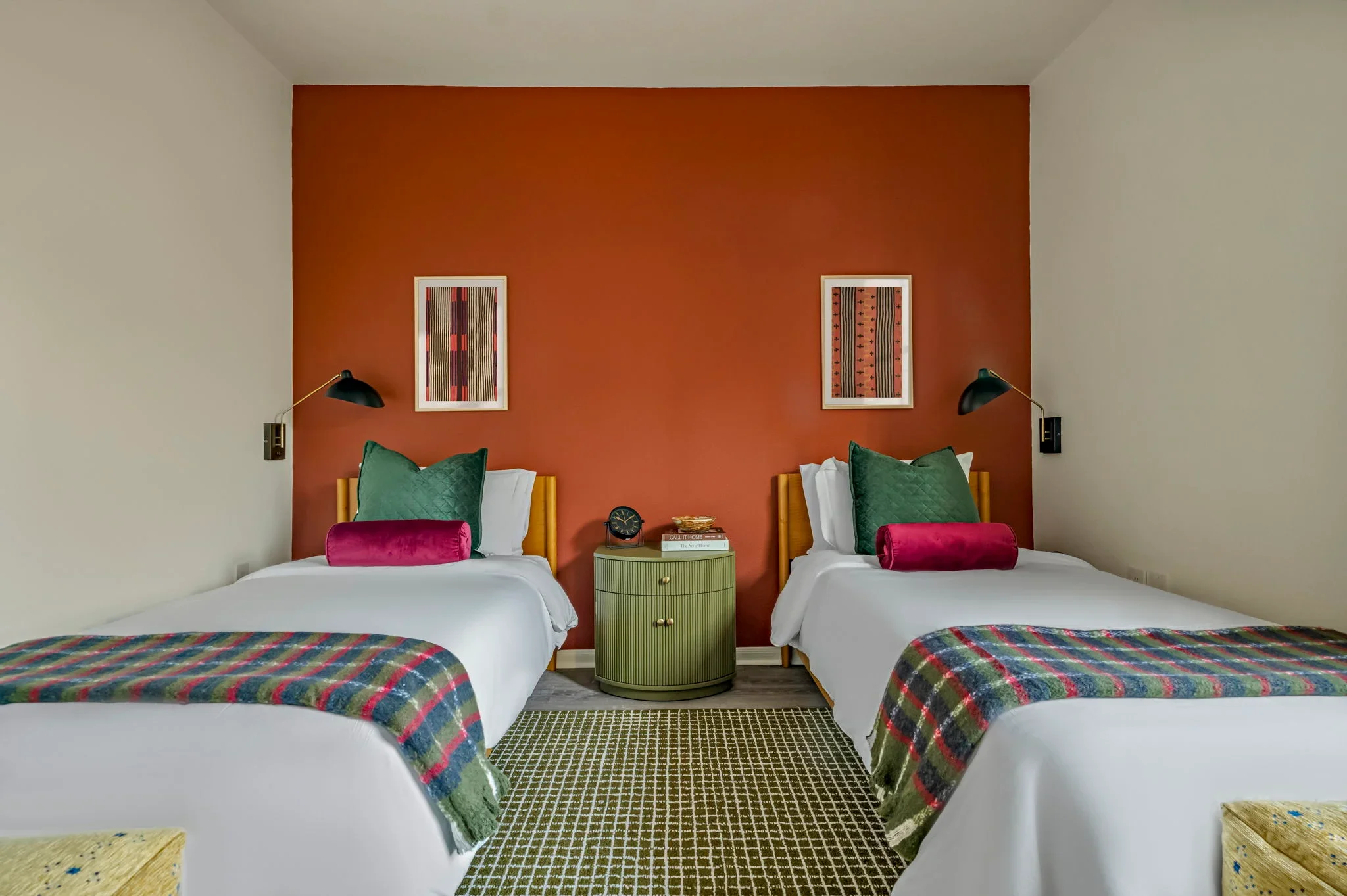 Airbnb double bedroom design detail with terracotta accent wall, green velvet pillows, plaid throws, and green nightstand — Austin TX.
