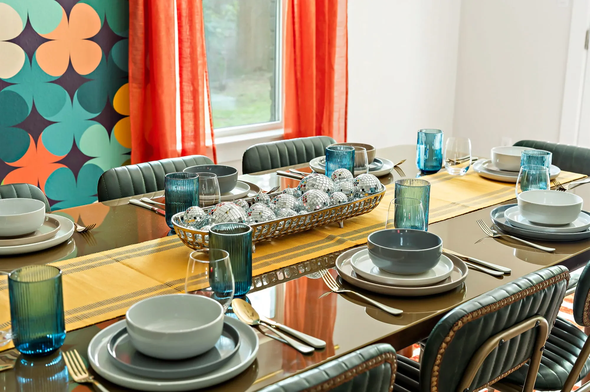 Dining table with blue and grey table settings, disco ball decor, and wooden tabletop.