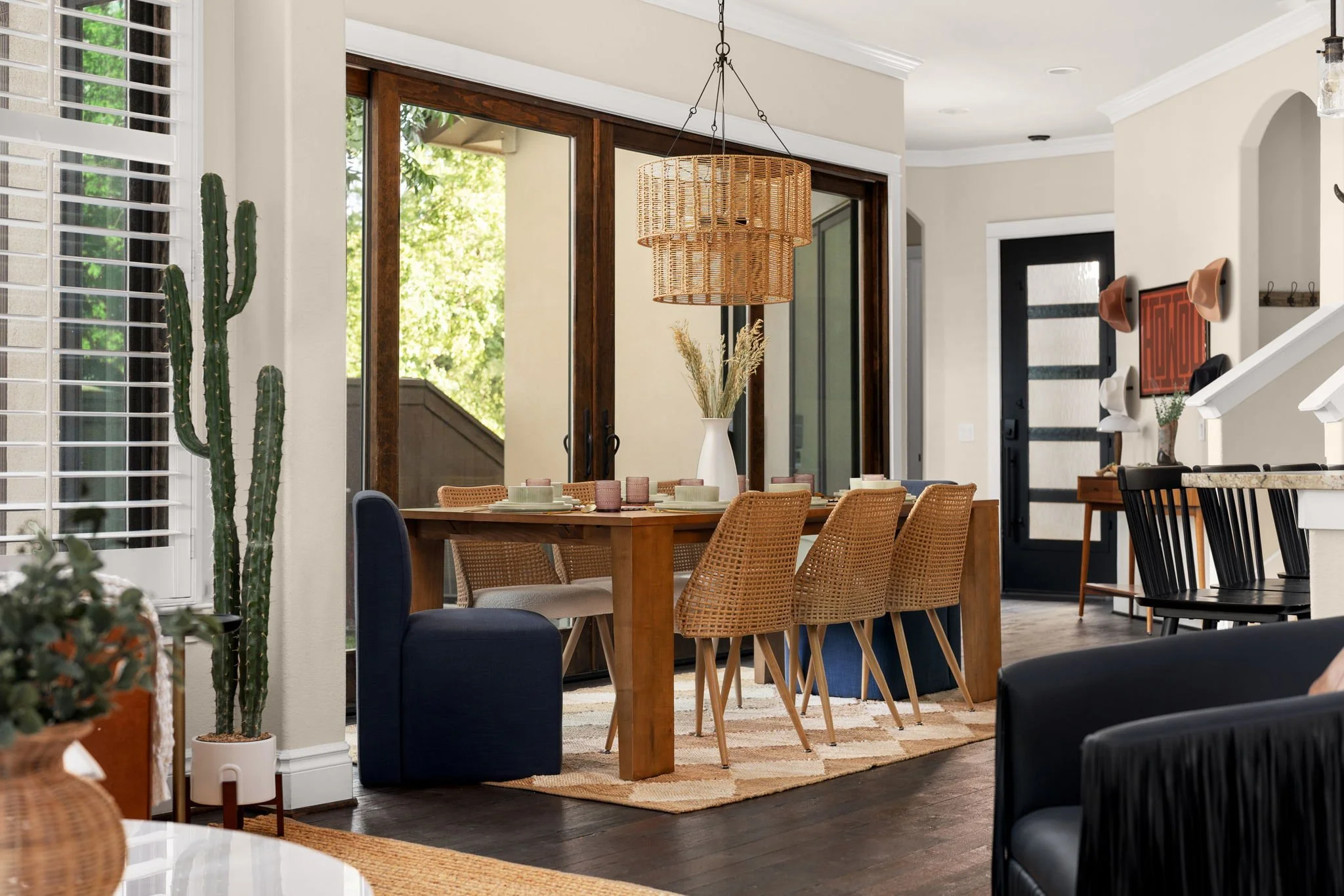 Airbnb dining room design with woven chandelier, rattan chairs, tall cactus, and sliding glass doors — Austin TX