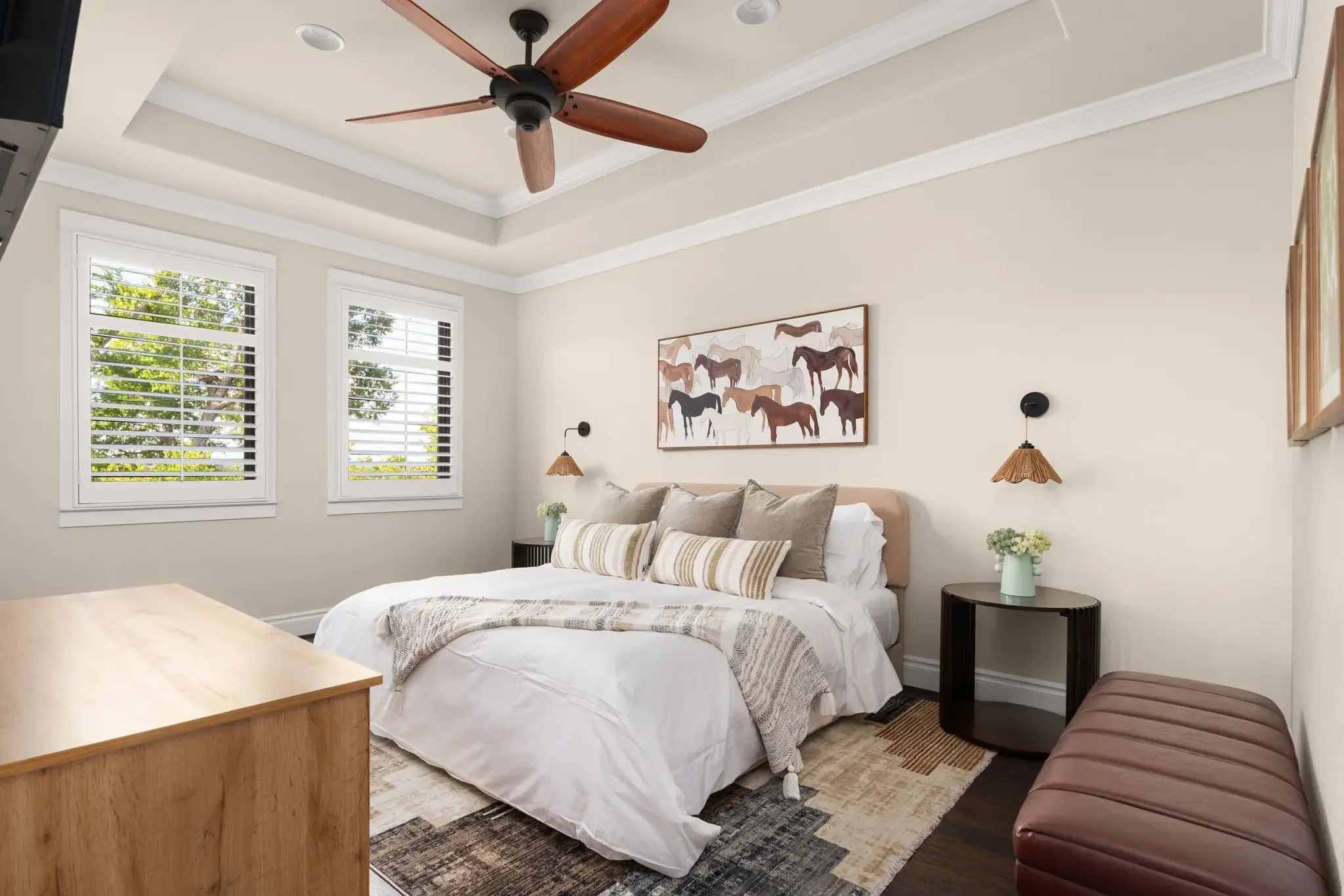 Short-term rental bedroom design with horse artwork, rattan sconces, layered bedding, and tray ceiling — Austin TX.