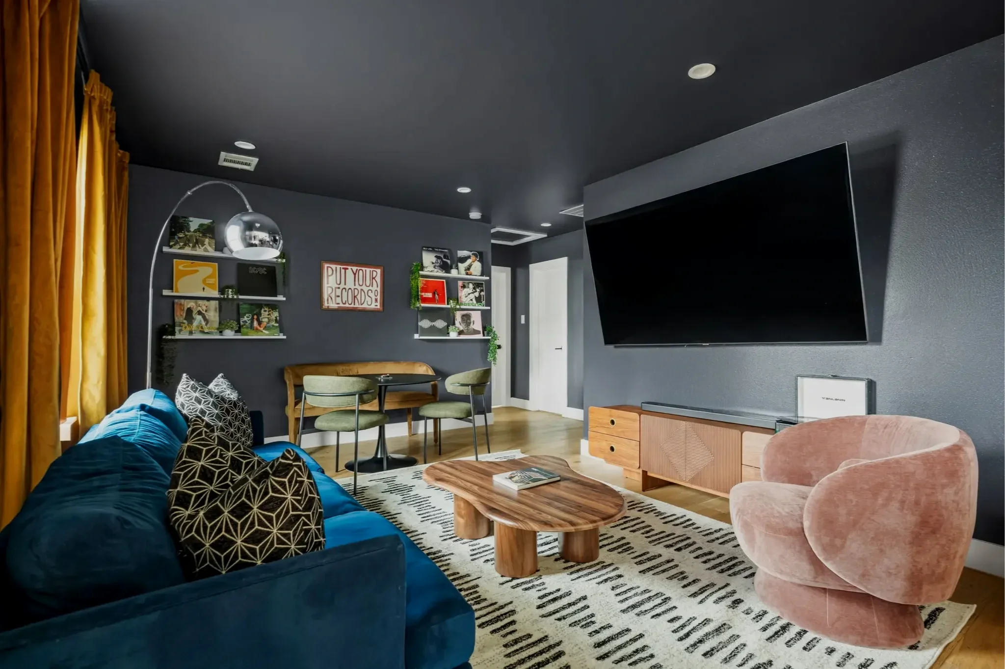The Gallery + Vinyl House short-term rental design project — moody living room with blue velvet sofa, gold curtains, and dark ceiling.