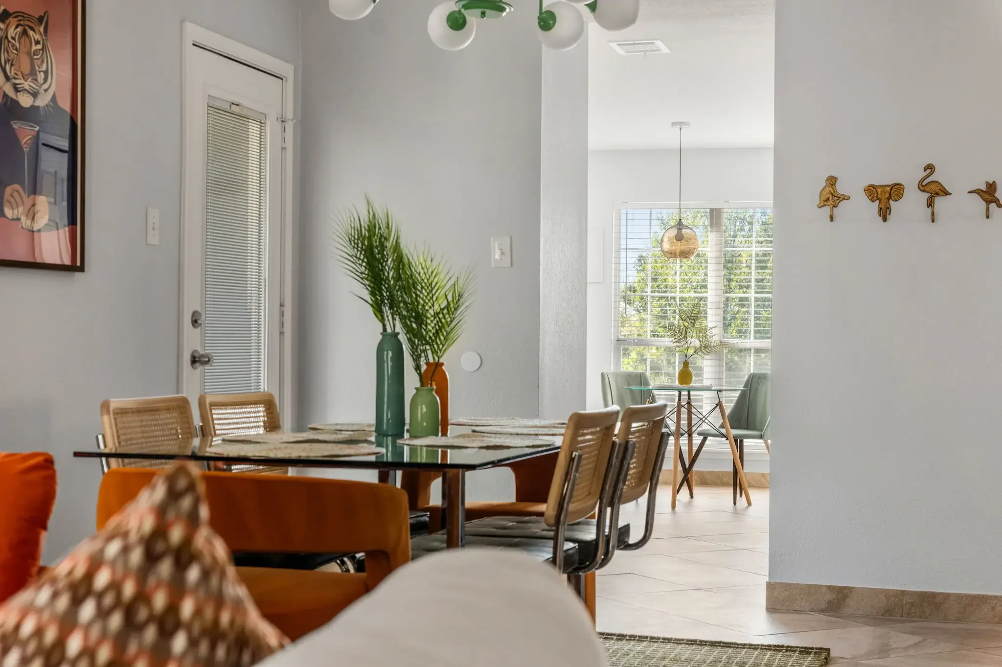 Airbnb dining area design detail with glass table, rattan chairs, tropical plants, and eclectic wall decor — Austin TX.