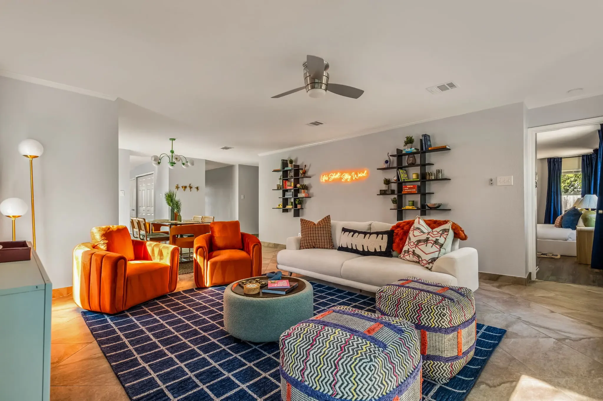 Short-term rental living room design with bold orange and teal seating, zebra print rug, and eclectic decor — Austin TX.